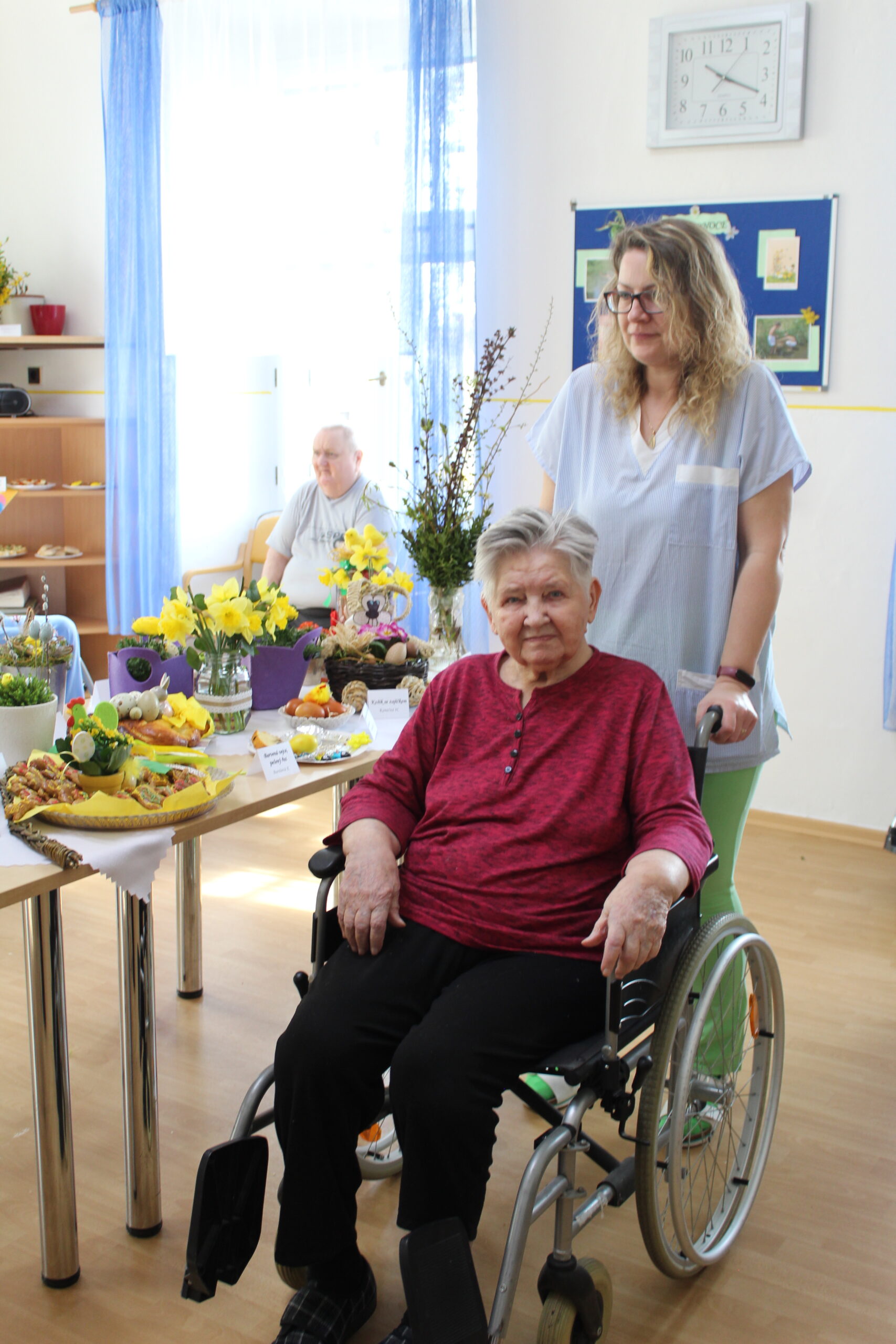Uživatelka na invalidním vozíku si prohlíží velikonoční dekorace a pokrmy.