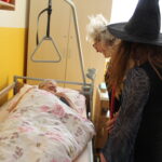 Čarodějnice stojí u postele na pokoji domova.