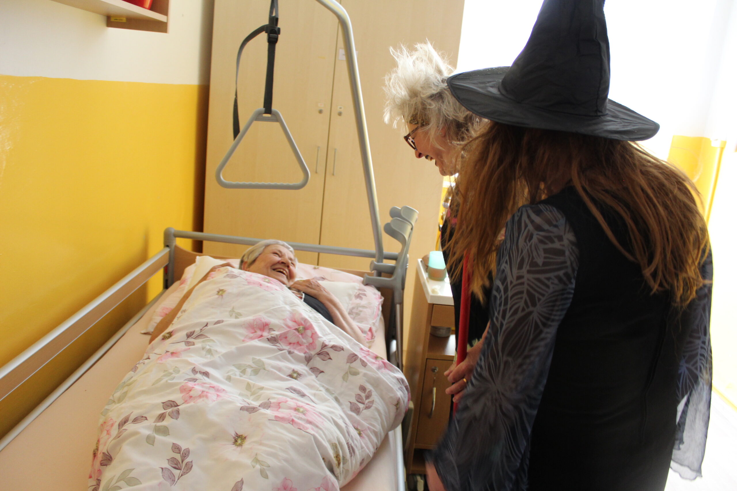 Čarodějnice stojí u postele na pokoji domova.